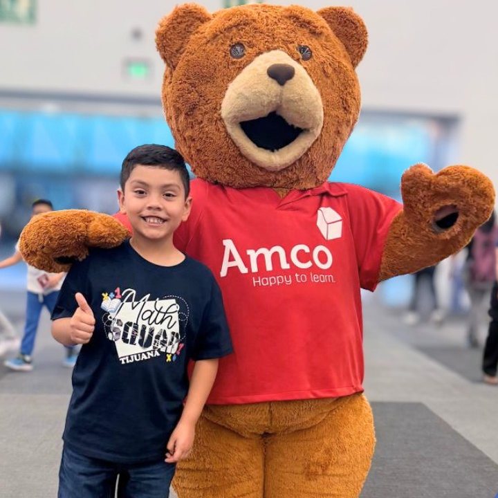 Alumno con la mascota de AMCO en el Summit Internacional