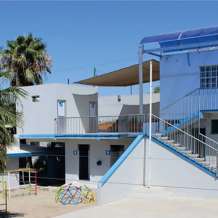 Patio interior con palmeras, juegos infantiles y edificios de dos niveles