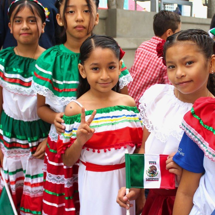 Alumnas de Primaria con trajes regionales y banderas